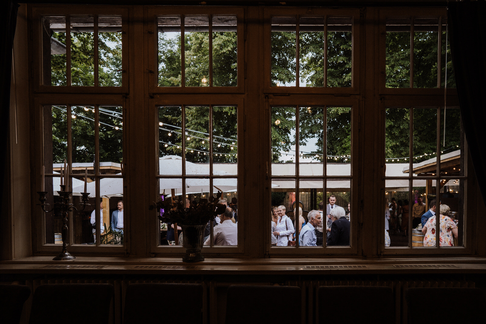 Blick aus dem Innenraum auf Gäste im Außenbereich der Villa Mediterrane in Bielefeld