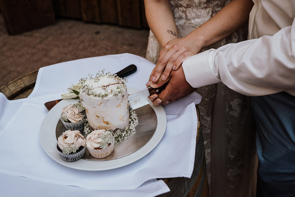 Hände schneiden eine Hochzeitstorte bei einer Feier in der Villa Mediterrane in Bielefeld