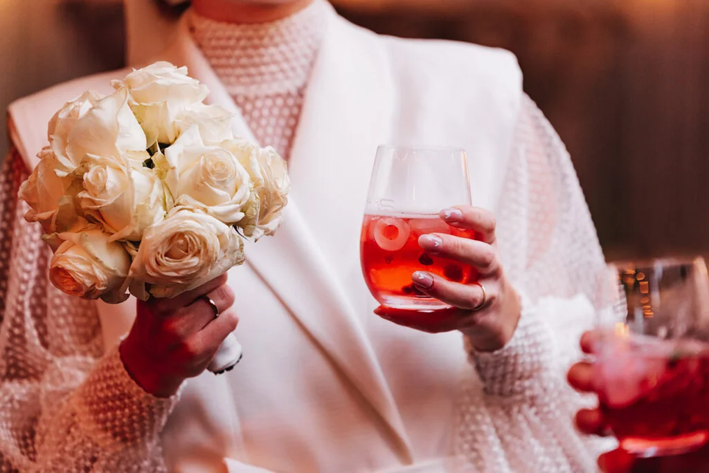 Person hält Brautstrauß und rotes Getränk bei einer Feier in der Villa Mediterrane in Bielefeld